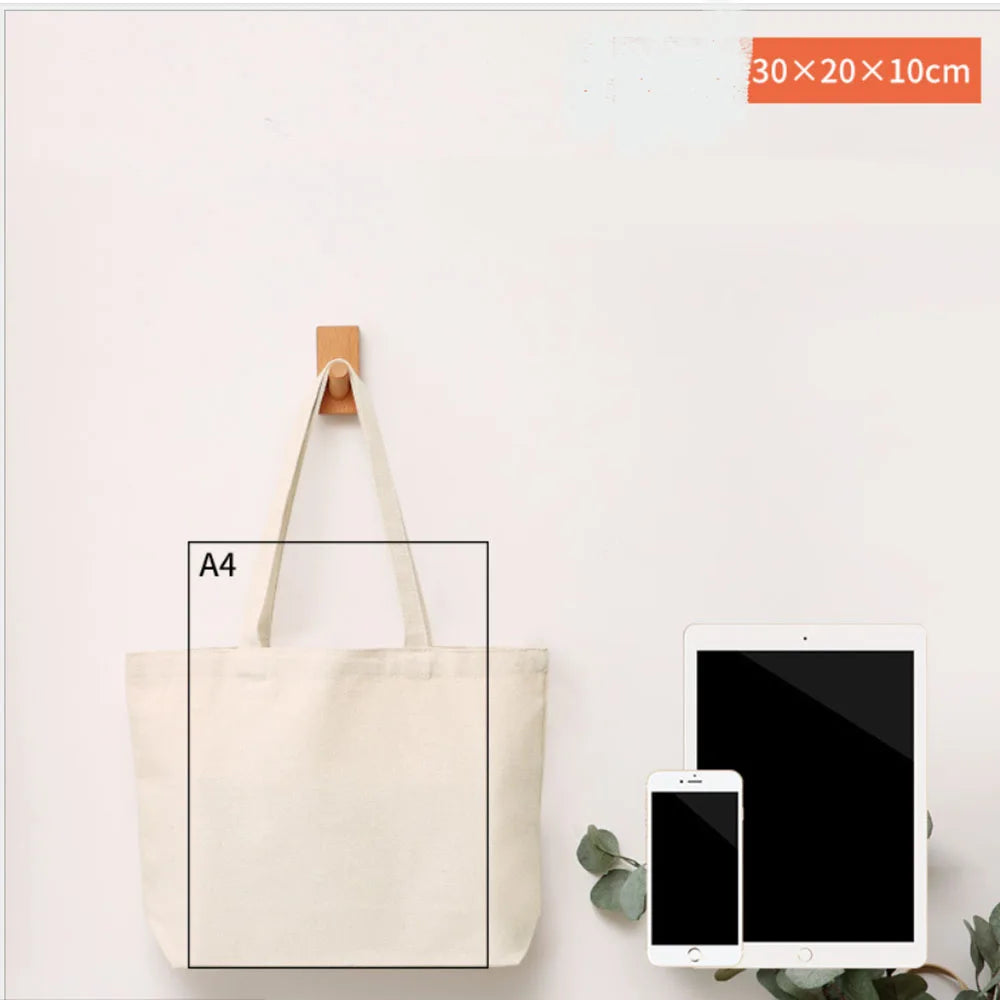 A natural canvas tote bag with light beige straps is displayed next to a tablet and a smartphone.