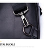 Close-up of a black leather bag showing a silver metal buckle closure.