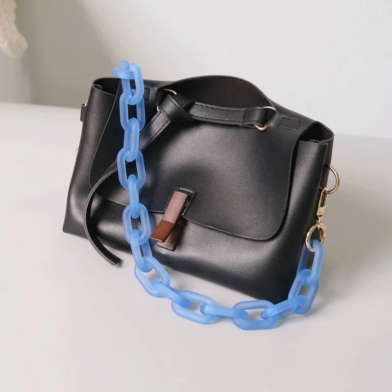 Schwarze Lederhandtasche mit hellblauer Kettchenriemen und braunem Lederakzent.