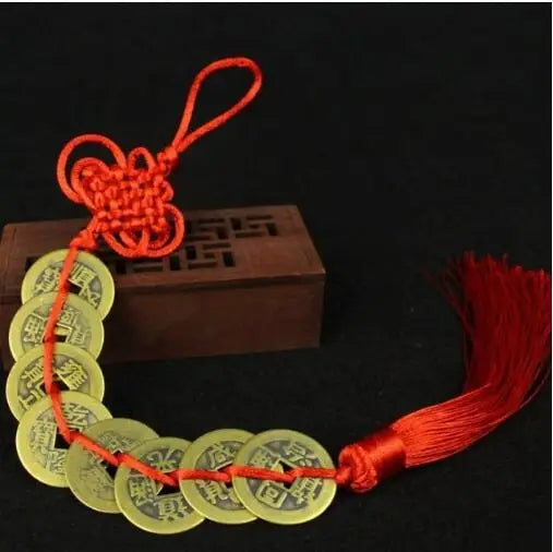 A necklace made of gold coins tied with a red handmade knot, used for Chinese Feng Shui wealth.