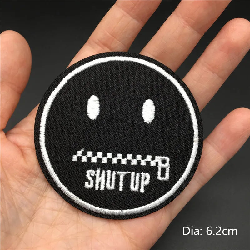 Black embroidered punk skull patch with a mouth showing teeth and the text SHUT UP on a hand