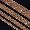 Close-up of a gold crystal rhinestone ribbon with sparkling glitter texture laid diagonally on a dark background.