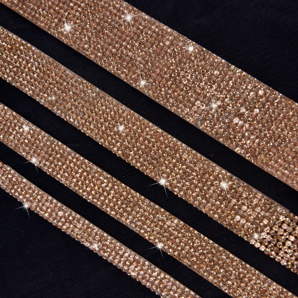 Close-up of a gold crystal rhinestone ribbon with sparkling glitter texture laid diagonally on a dark background.