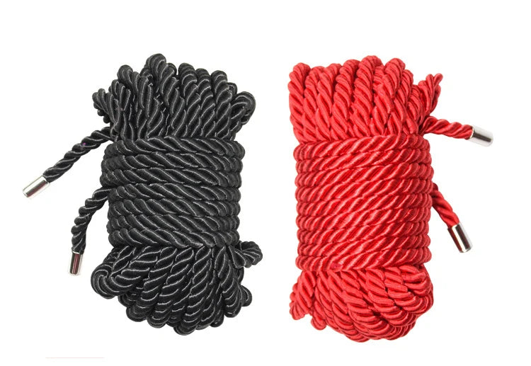 A pair of thick braided ropes, one black and one red, used for bondage or roleplay.
