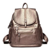 A brown faux leather women's backpack with multiple compartments shown from the back.