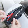A hand is removing a black and white mirror visor from a car's side mirror.