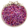A round container filled with mixed glass seed beads in shades of purple and pink, tied with a bow.