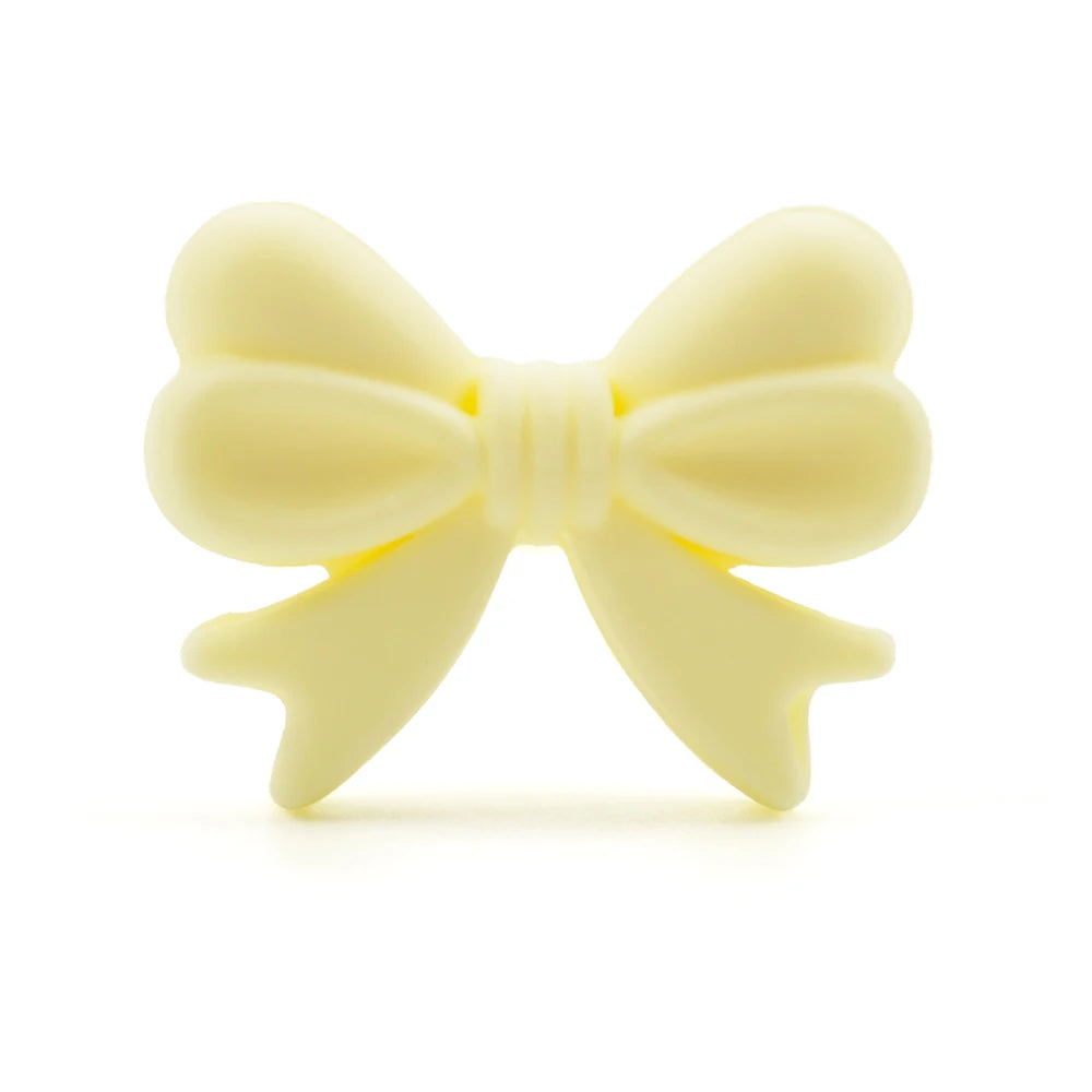 A pale yellow food-grade silicone bow or crown bead for jewelry making and DIY crafts.