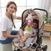 A woman holds a soft plush baby rattle toy with hanging bell and cartoon animal mobile in a stroller for newborns.