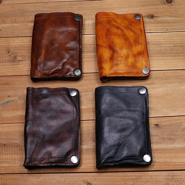 Four genuine leather bifold wallets in brown, dark brown, and black colors displayed on a wooden surface.