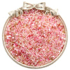 A circular dish filled with pink and clear glass seed beads tied with a bow for jewelry making