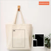 A beige canvas tote bag with a black square label is displayed against a white background.