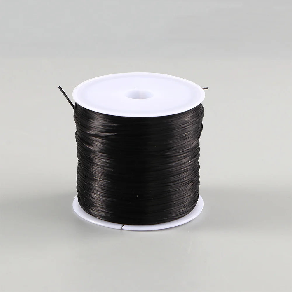A spool of black elastic crystal beading cord for jewelry making with a white plastic core.