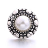 Silver metal snap buttons with a central pearl surrounded by textured metal dots for jewelry making