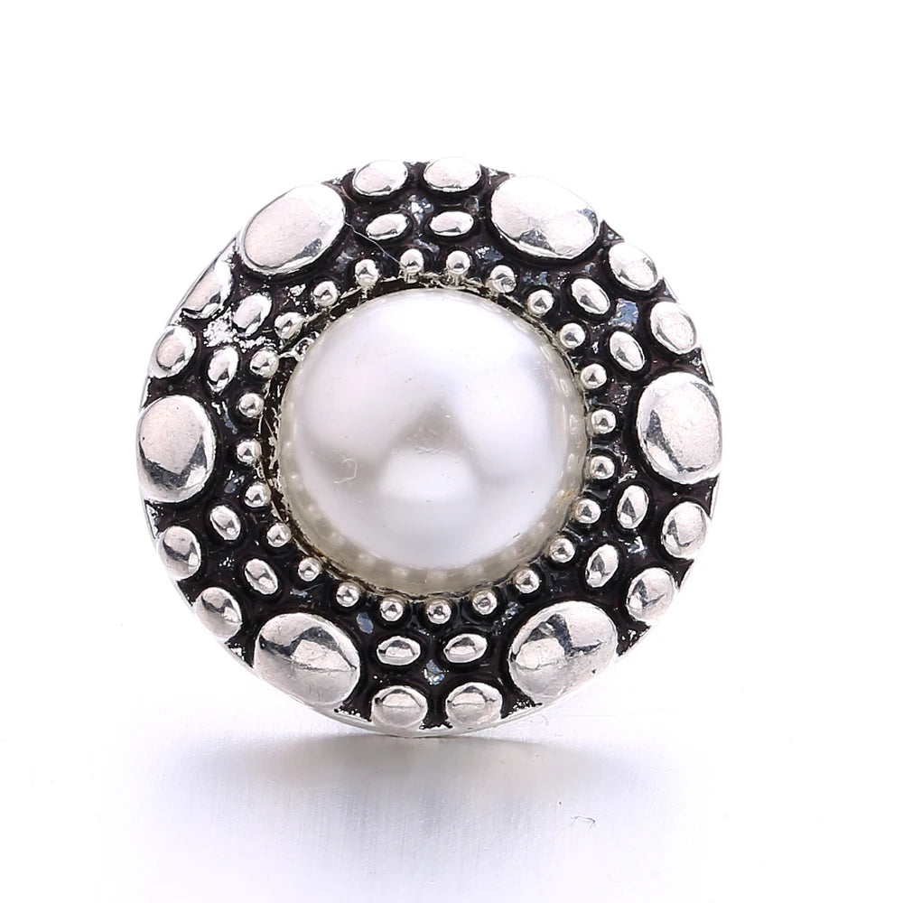 Silver metal snap buttons with a central pearl surrounded by textured metal dots for jewelry making