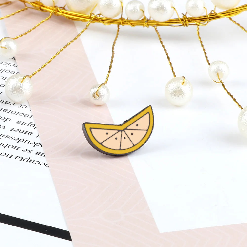 A gold wire fruit brooch pin featuring small white pearl-like beads hanging from a delicate wire.