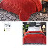 A close-up of a luxurious, thickened red velvet bedspread with a quilted pattern draped on a bed.