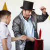 A magician in a sparkly jacket performs a trick with a magic bag and a red flower.