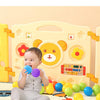 A baby is playing with colorful soft play pit balls in a yellow and white themed environment.