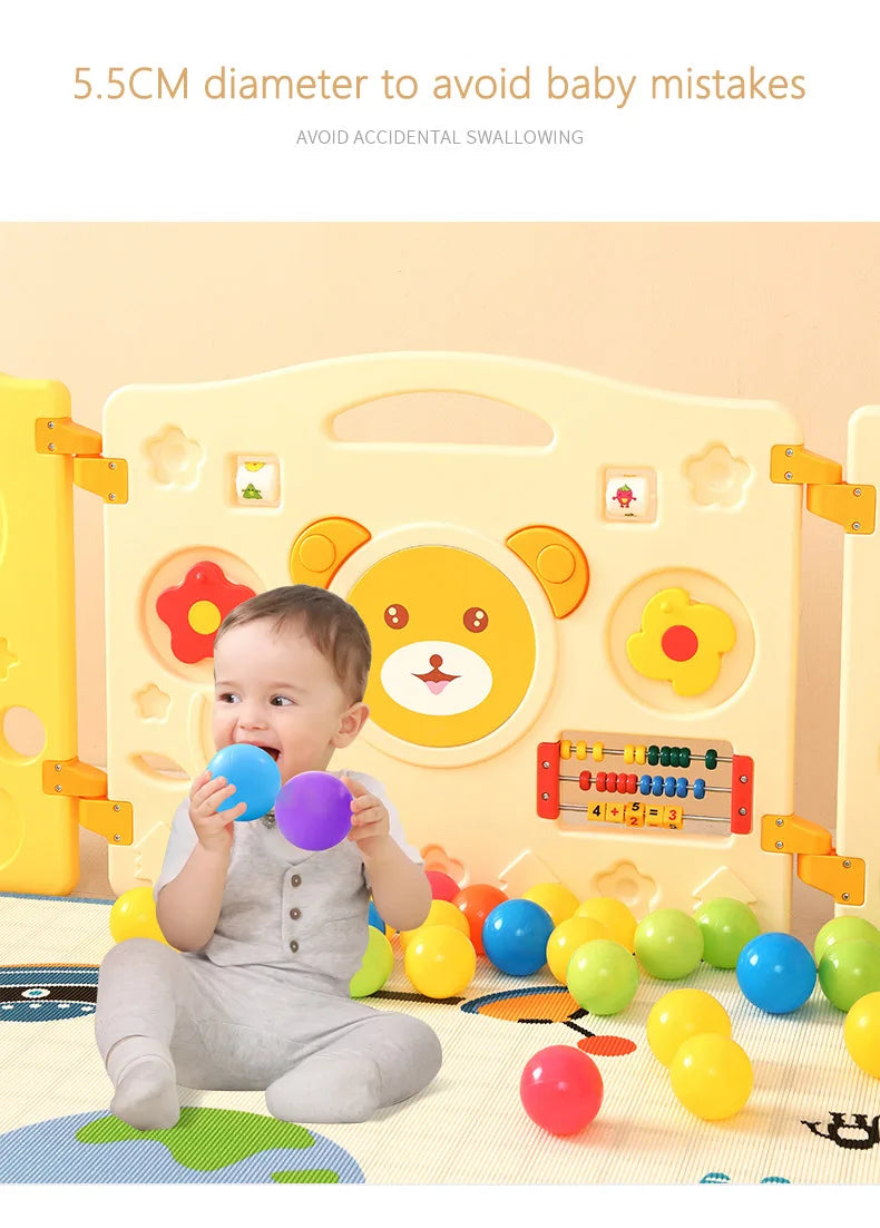 A baby is playing with colorful soft play pit balls in a yellow and white themed environment.