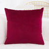 A deep burgundy velvet decorative cushion cover resting on a white surface.