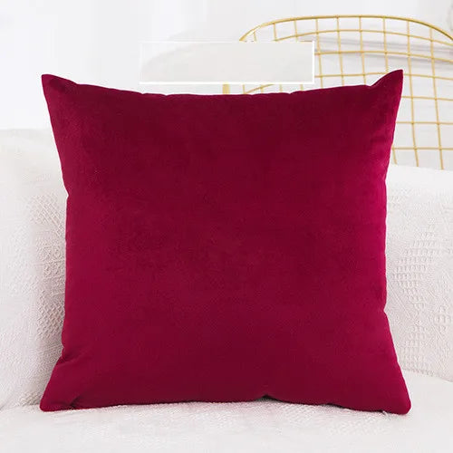 A deep burgundy velvet decorative cushion cover resting on a white surface.