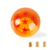 A glossy orange shift knob with a star design is shown next to several small brass rings.