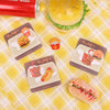 Several food-themed embroidered iron-on patches featuring burgers and other food items are displayed on a yellow plaid fabric