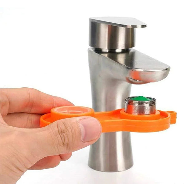 Eine Hand hält ein Entfernungswerkzeug für einen orangefarbenen Wasserhahnaufsatz neben einem Edelstahl-Wasserhahnkopf.