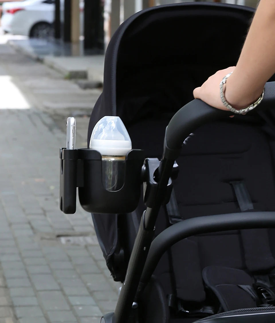 A black stroller features a mounted cup holder for drinks and a phone holder.