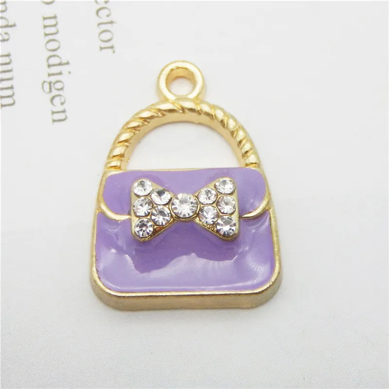 Gold-toned pendant featuring a lavender enamel handbag charm with a sparkling bow detail