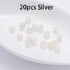 20 pieces of silver silicone rubber ear back stoppers arranged on a white plate.