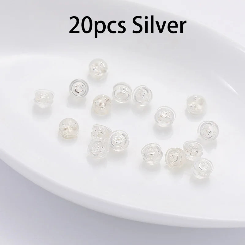 20 pieces of silver silicone rubber ear back stoppers arranged on a white plate.