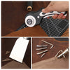 A hand holds a professional leather craft tool kit with a blade and a grooving tool on a dark wooden surface.