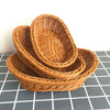 A stack of handwoven wicker serving baskets in natural brown color on a gray checkered surface.