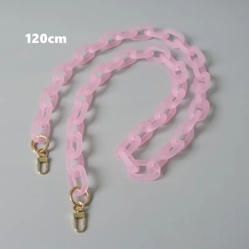 Rosa abnehmbare Kettenriemchen für eine Tasche, ausgebreitet auf einer grauen Oberfläche.
