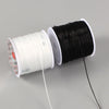 A spool of black elastic crystal beading cord next to a spool of white elastic crystal beading cord.