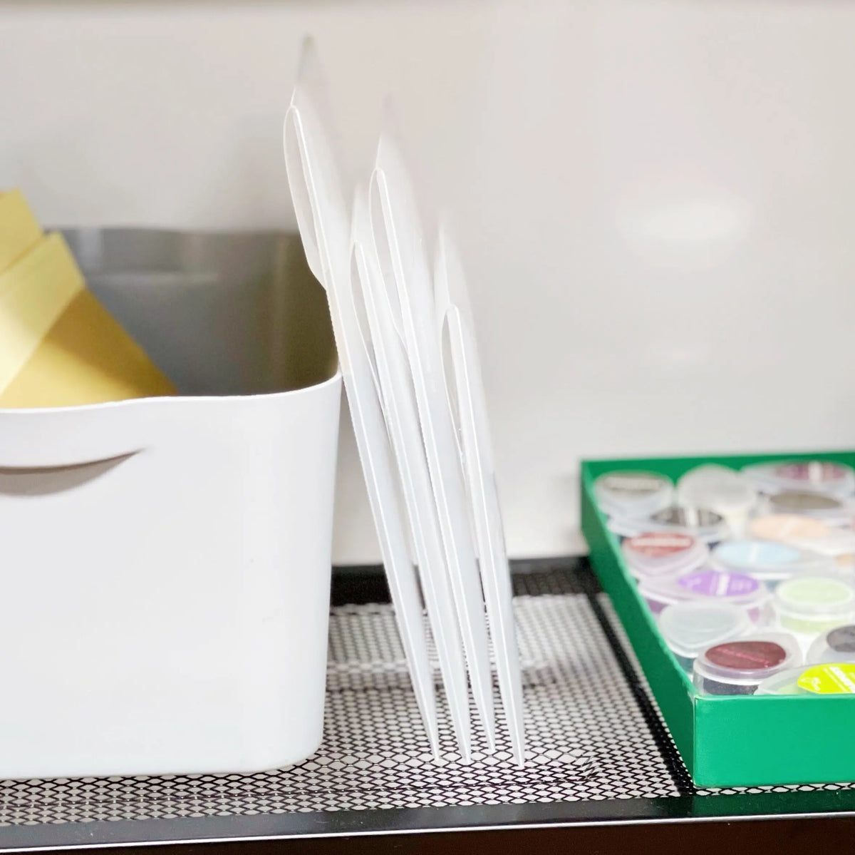 A white container holds a set of clear plastic stamps and die for card making on a black tray.