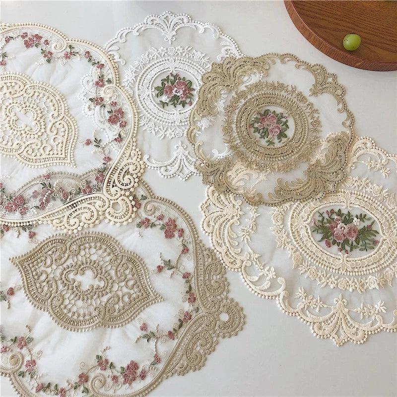 Elegant oval lace embroidered placemats featuring delicate floral patterns in beige and pink on white fabric