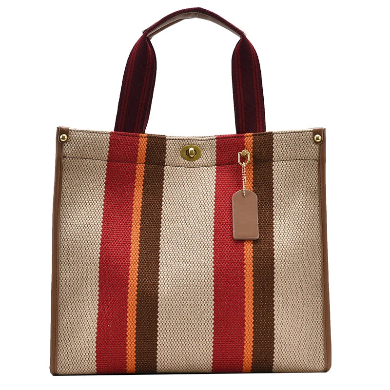 A beige canvas tote bag with vertical stripes of red, brown, and orange, featuring a leather strap.