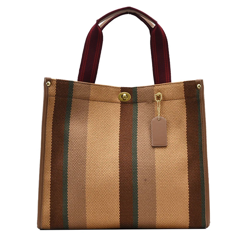 A tan canvas crossbody tote bag with brown stripes and a maroon strap.
