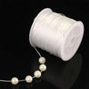 White elastic crystal beading cord coiled on a spool with a string of pearls unwound.