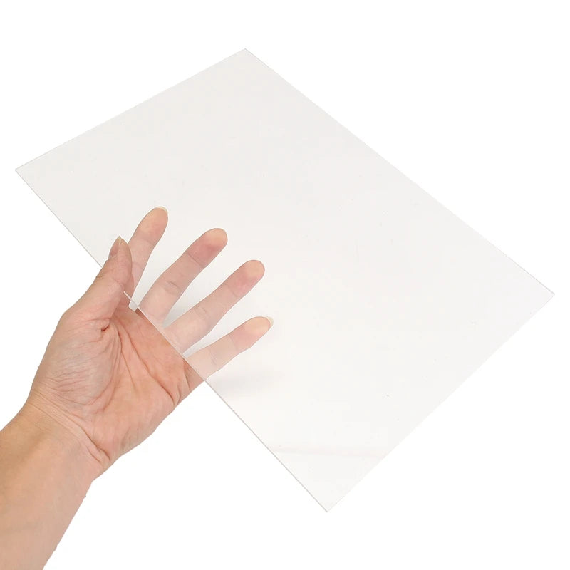 A hand is holding a clear acrylic sheet, showing its transparency and thickness.