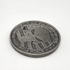A round, dark silver commemorative coin featuring a stylized two-gun design and text related to terrorism force.