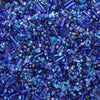 A close-up view of mixed glass seed beads in various shades of blue and purple.