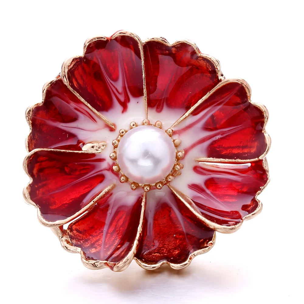 A red and white floral enamel button with a pearl center, featuring gold-toned metal edges.