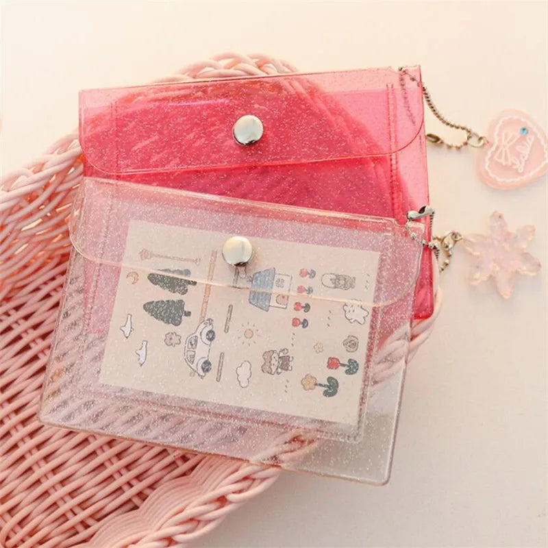 A pink glitter PVC card holder with a clear overlay featuring various small decorative elements and a silver clasp.