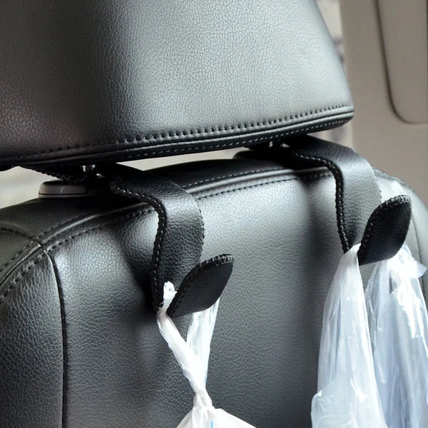 Close-up of black leather car seat headrest hooks attached to a gray seat cushion.