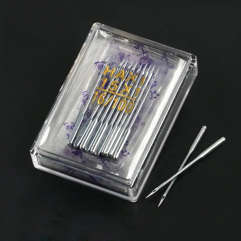 A clear plastic box containing a multi-pack of sewing machine needles with purple markings and a silver pair of tweezers.