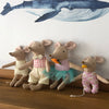 A group of adorable stuffed deer toys in various outfits and colors displayed against a white wall.